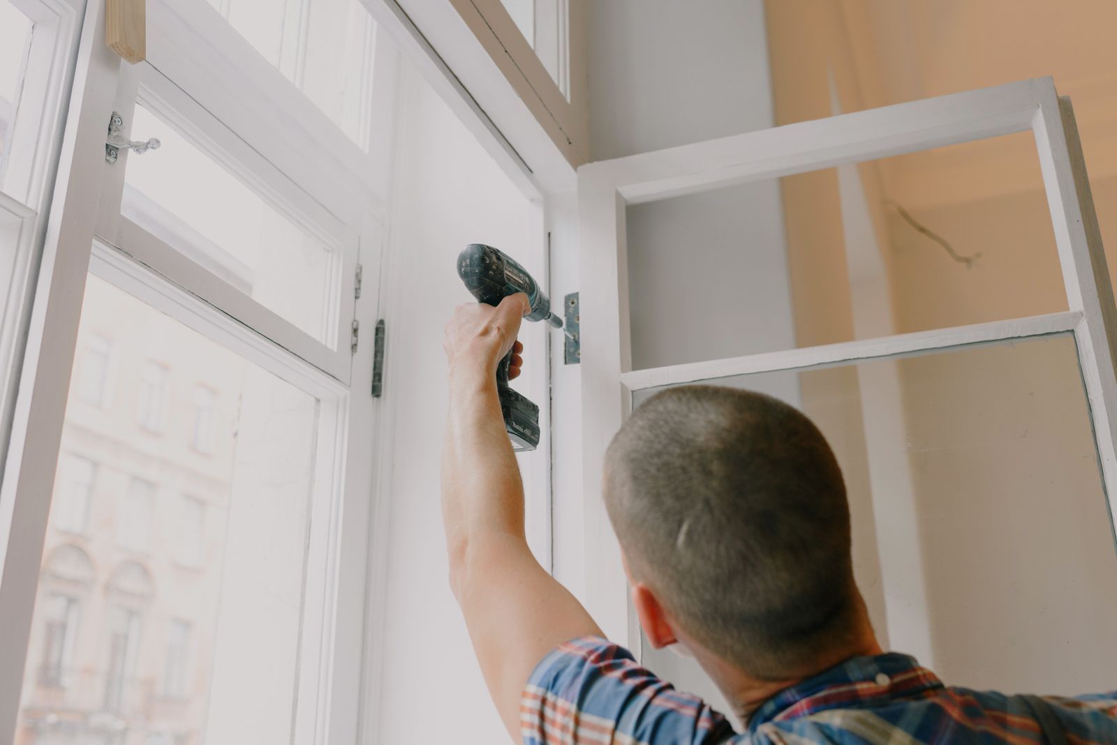 Serrurier ajustant un bâti de porte à la perceuse
